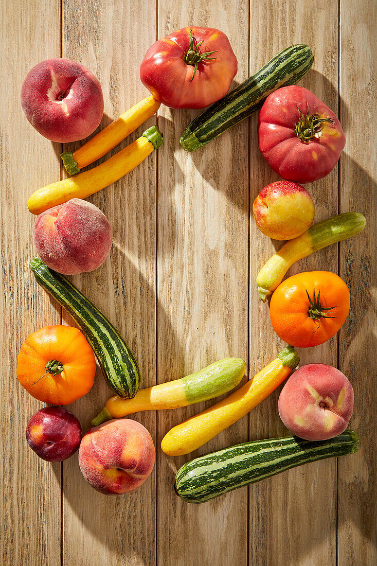 Tomatoes, courgettes and stone fruit on a wooden base