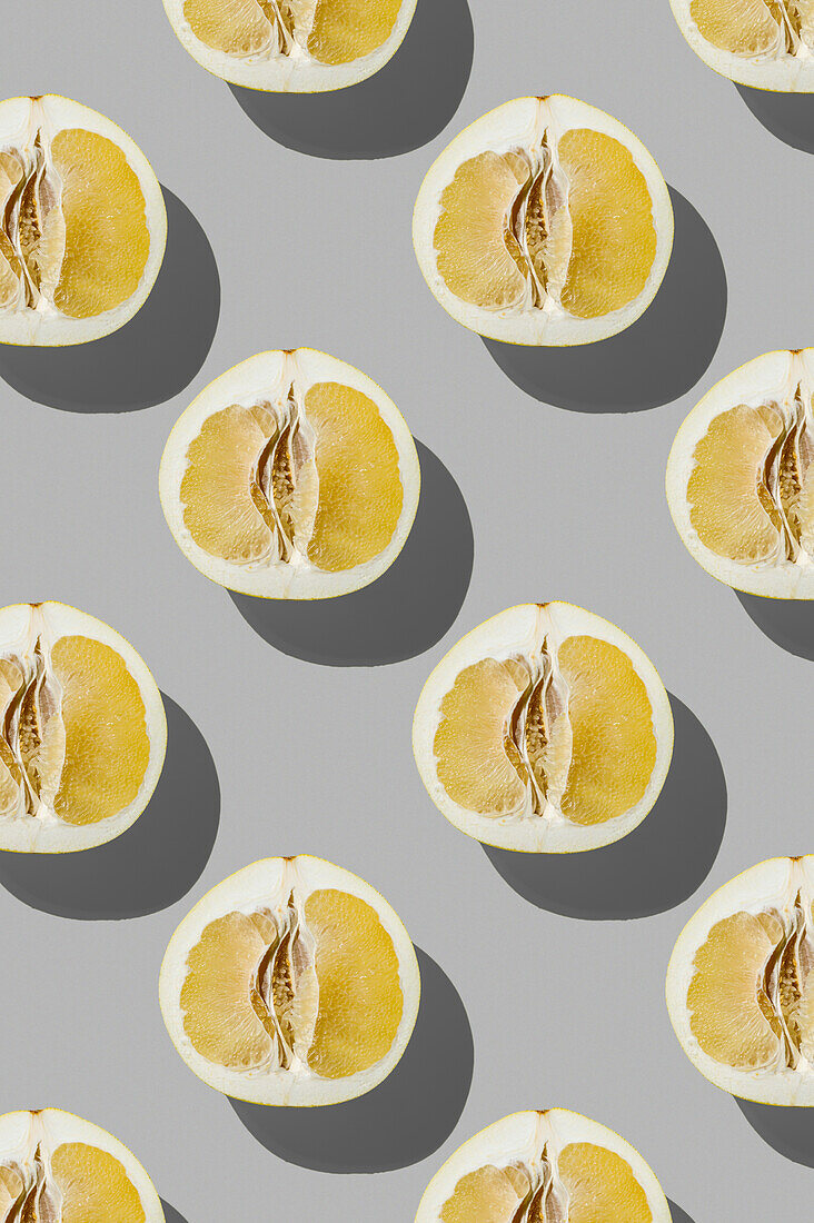 Vertical pattern of fresh half pomelo fruit on grey background flatlay food