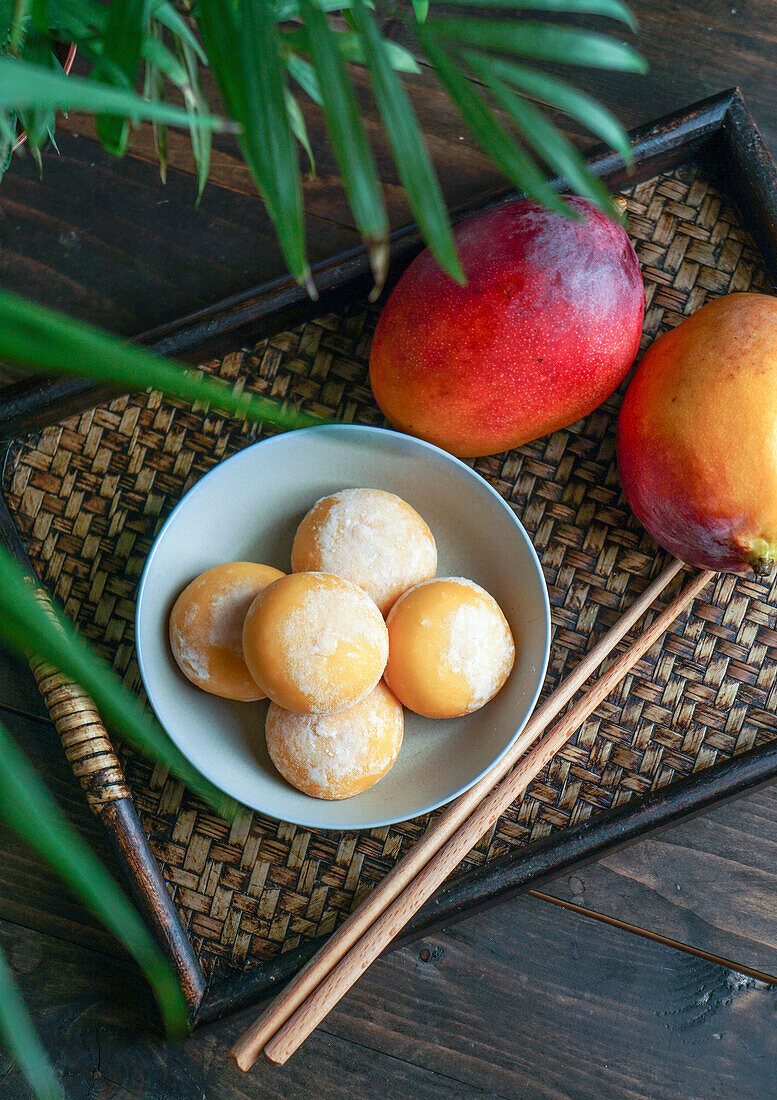 Japanische Mango-Mochi-Törtchen mit Eiscreme auf einem klassischen asiatischen Holztablett