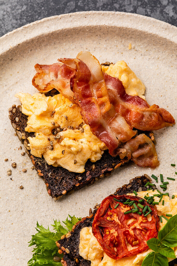 Scrambled eggs with bacon and tomato on toasted grain bread
