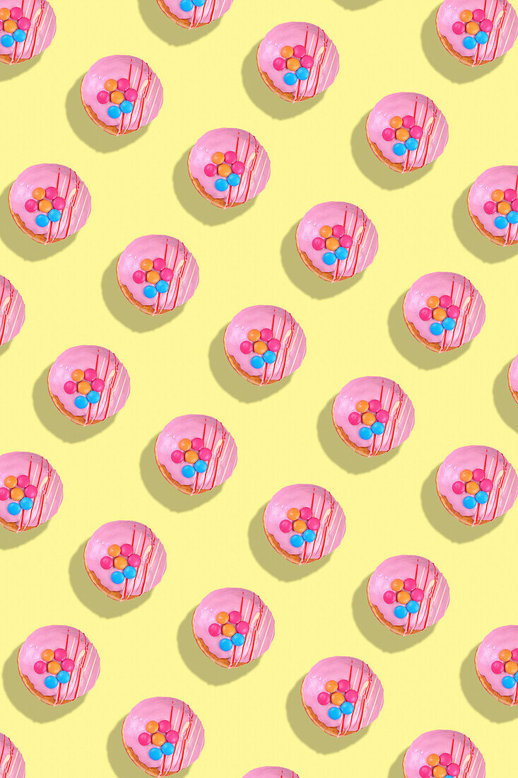 Modern retro color theme pattern of pink donuts against a yellow background.