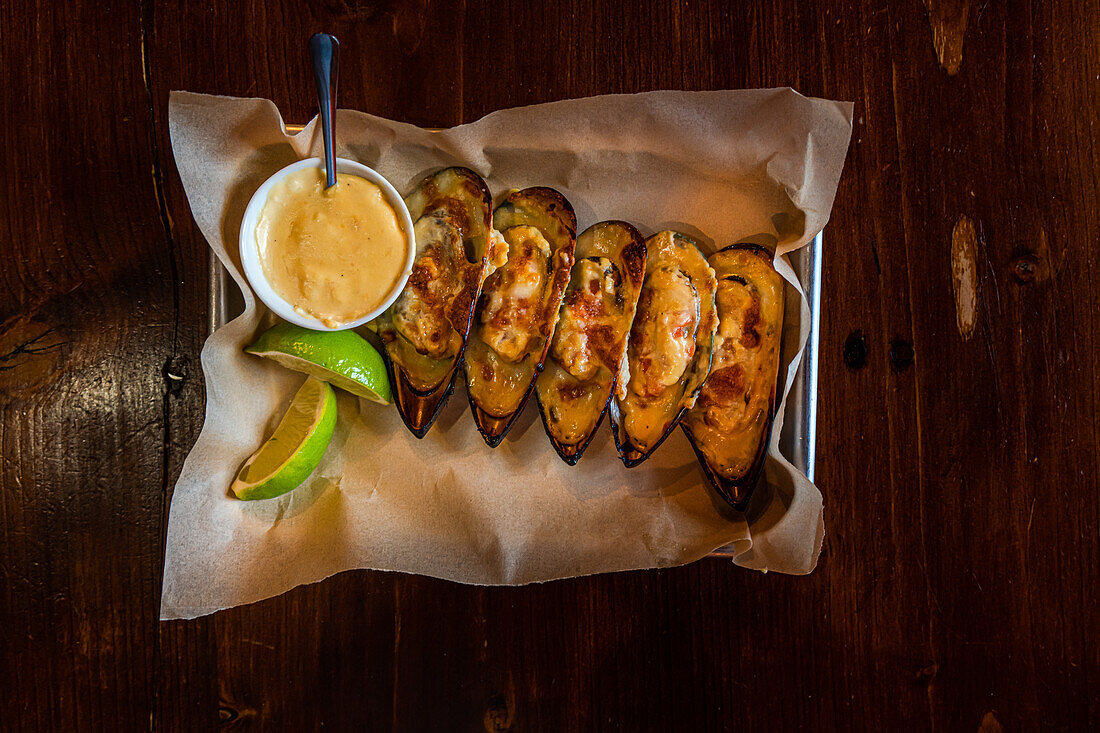 Baked shellfish mussels with cheese sauce served with lime slice