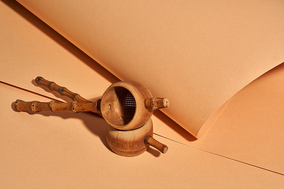 Hoher Winkel eines handgefertigten Bambus-Teefilters vor einem Hintergrund aus Bastelpapier mit einem schönen Atelier