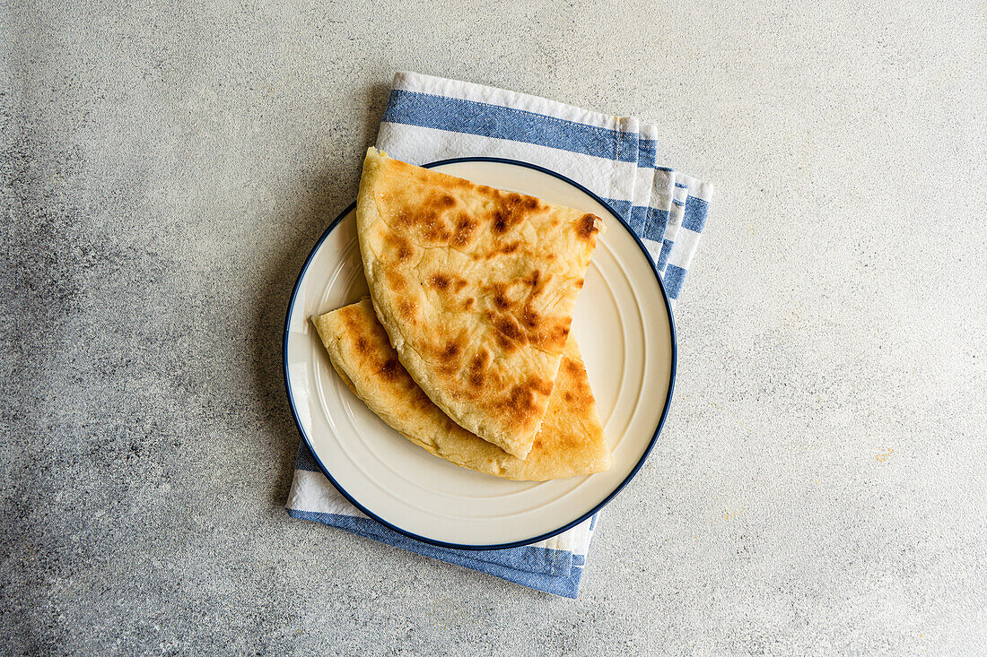 Draufsicht auf ein traditionelles georgisches Gericht: Imeruli khachapuri Brotkuchen mit Sulguni Käse auf dem Teller