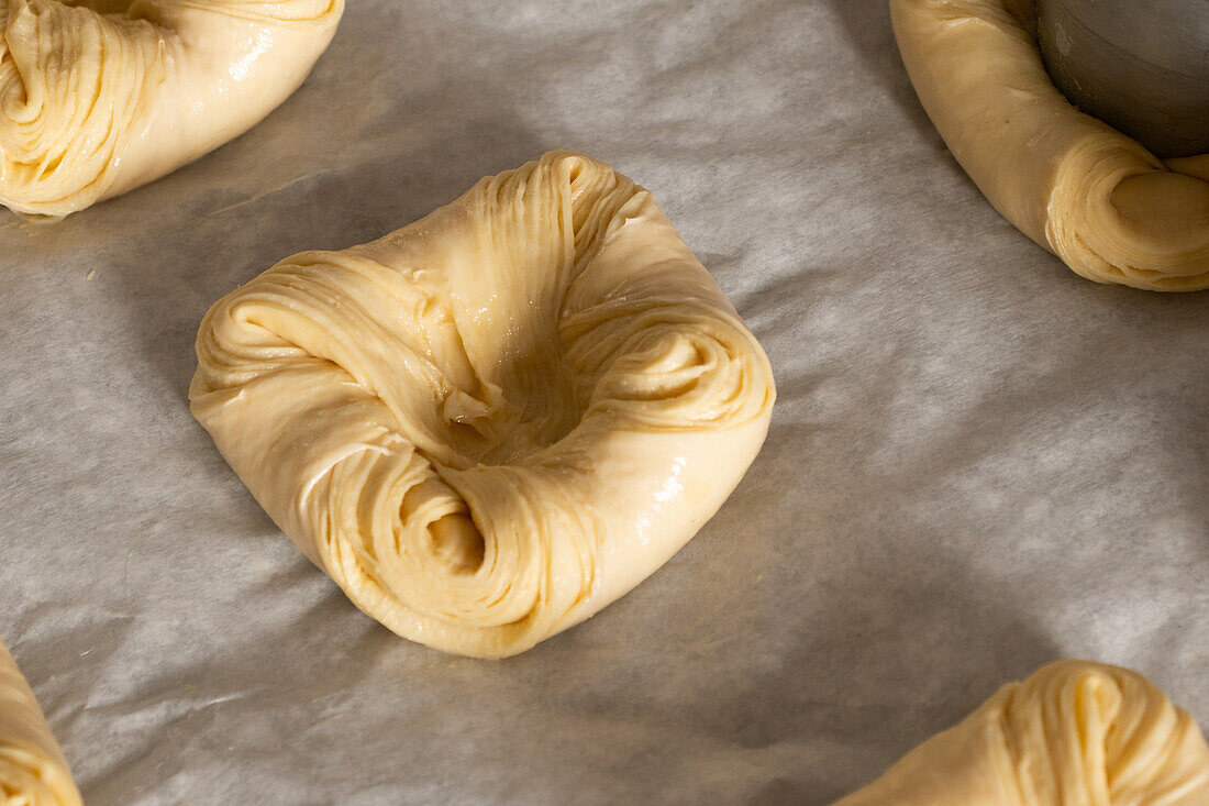 From above closeup shot of fresh raw twisted cinnamon bread dough placed on table in kitchen bakery at daylight