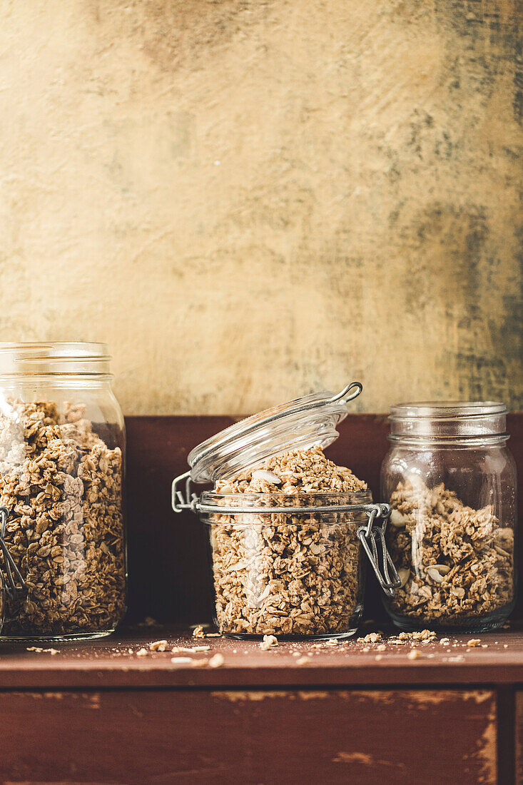 Homemade granola in a jar on a rustic kitchen sideboard