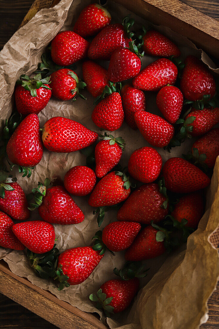 Wooden crate full of fresh strawberries on a wooden table