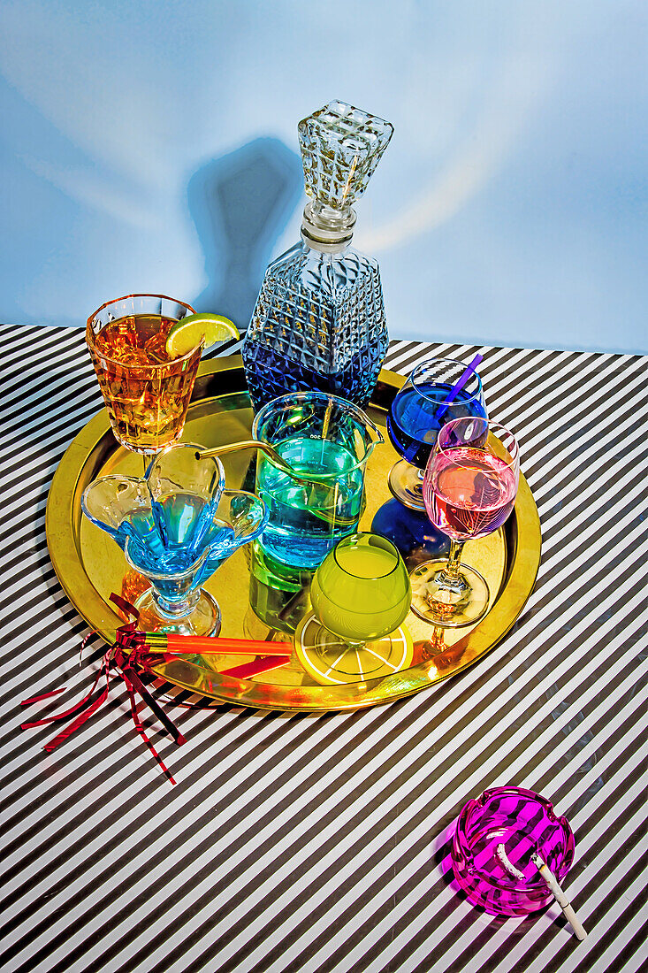 Von oben verschiedene Cocktails, bestehend aus blauem Margarita Long Island Eistee Wein Daiquiri in attraktiven Gläsern und Glas auf Teller auf gestreiftem Tuch vor blauem Hintergrund platziert