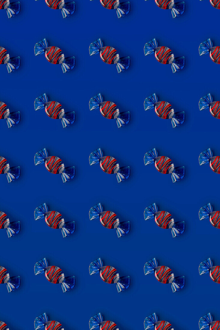 Top view of pattern of whole sweet crystal candies arranged on blue background