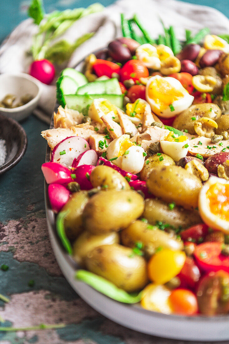 Köstlicher Salat Nicoise mit frischem Gemüse in einem Tablett auf dem Tisch (von oben)