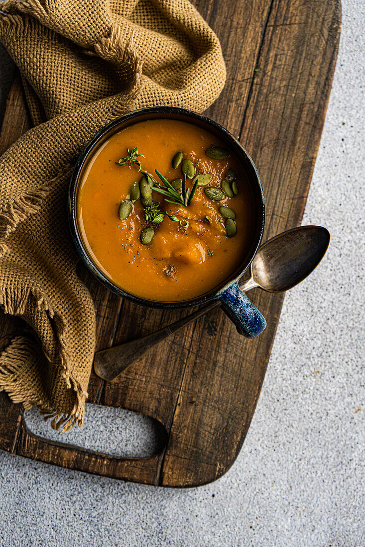 Leckere Kürbiscremesuppe mit Bio-Kräutern und Samen in blauer Vintage-Keramikschale