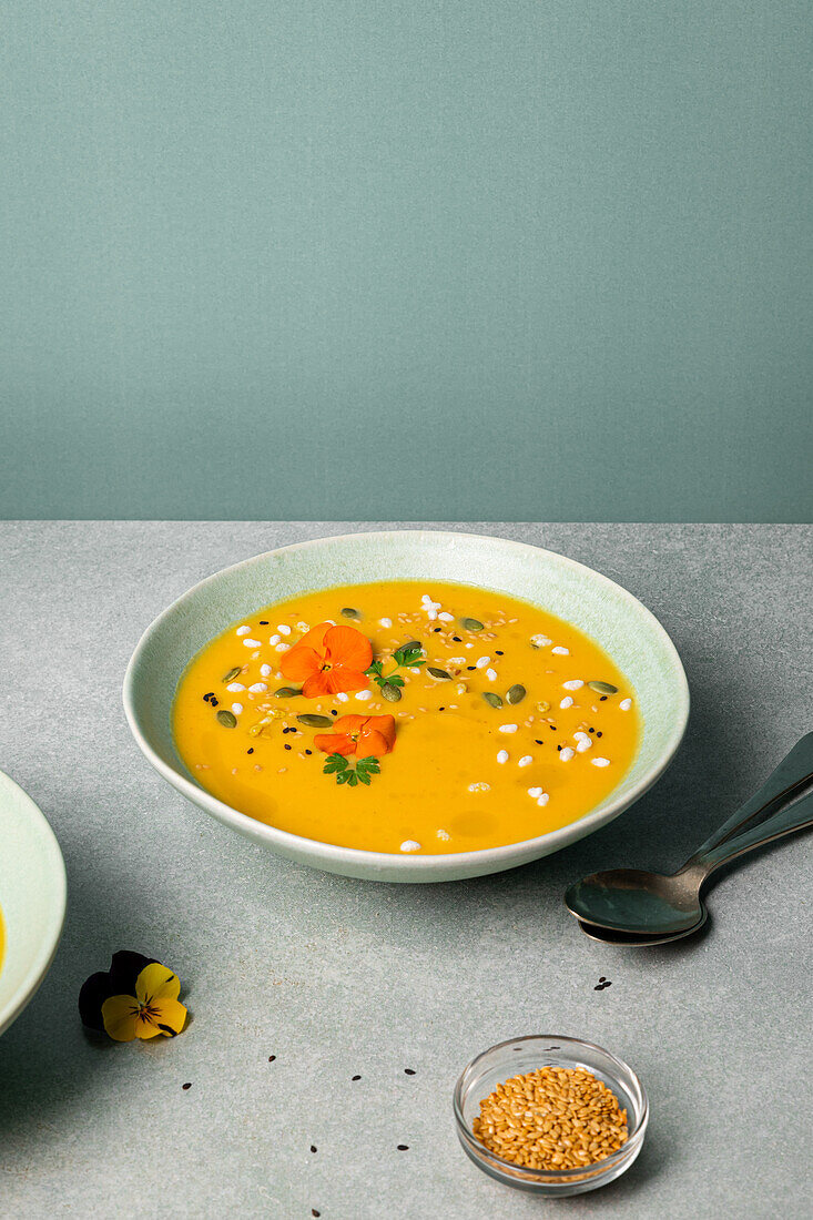 Appetizing vegetarian pumpkin cream soup with herbs and sesame seeds served in bowls on table