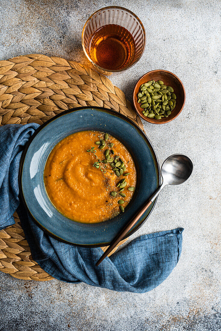 Leckere Kürbiscremesuppe mit Bio-Kräutern und Samen in blauer Vintage-Keramikschale