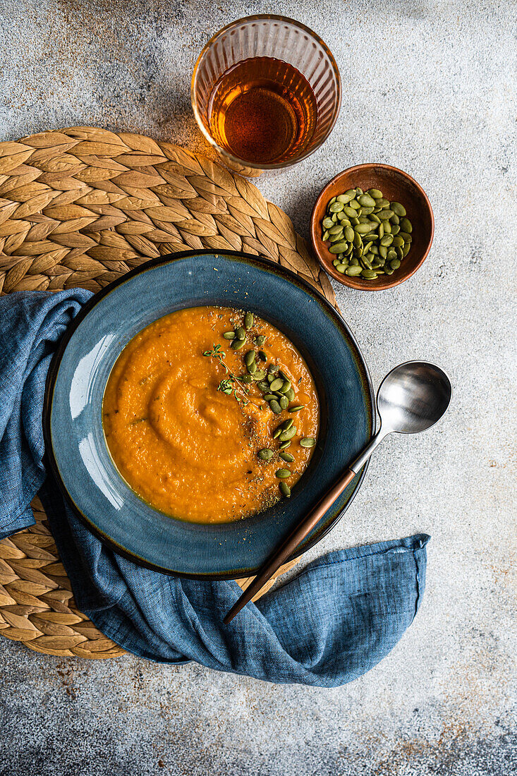Tasty pumpkin cream soup with organic herbs and seeds in blue vintage ceramic bowl