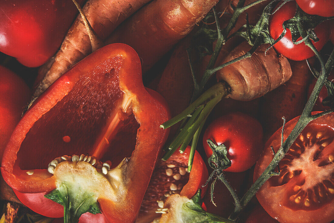 Food background with close up of raw orange and red vegetables: bell pepper, carrots and tomatoes. Healthy lifestyle with vitamins rich ingredients. Top view.