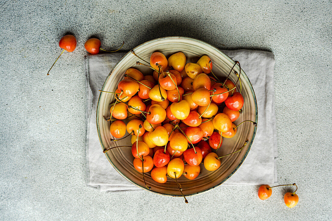 Bowl with organic ripe white sweet cherries on the concrete kitchen table