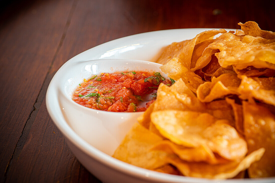 Mexikanische Mais-Chips mit Salsa-Sauce auf Holztisch