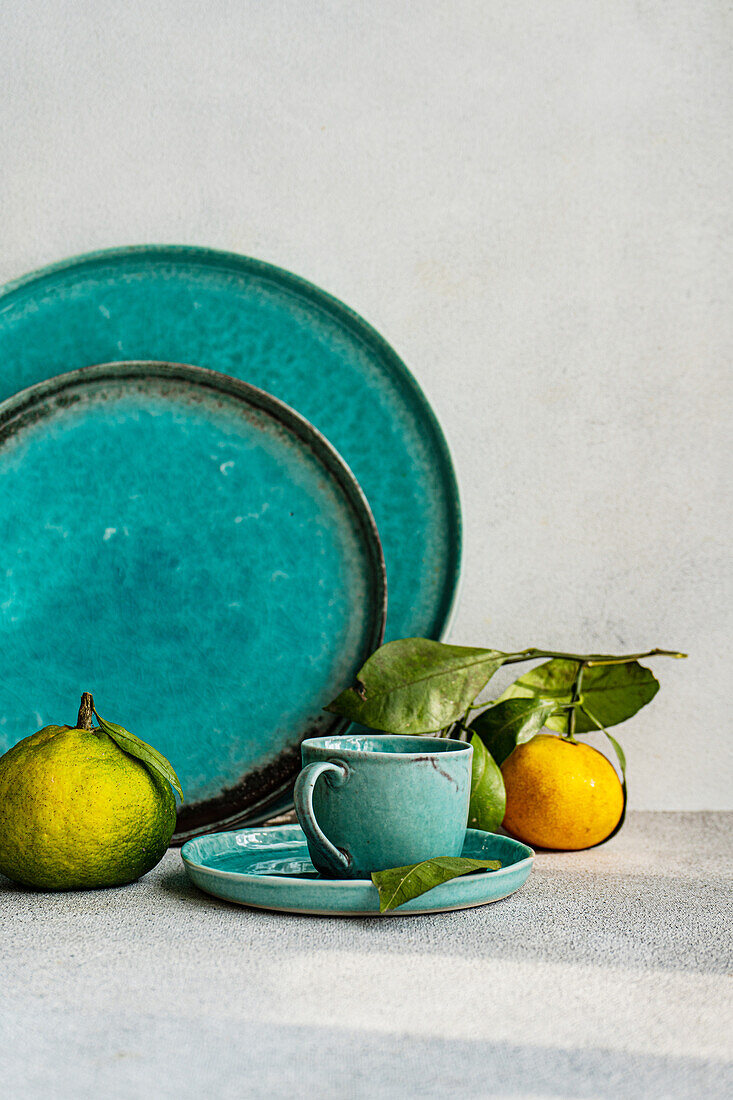 A beautifully arranged table setting in turquoise tones, complemented by fresh citrus fruits, creating an inviting dining atmosphere.