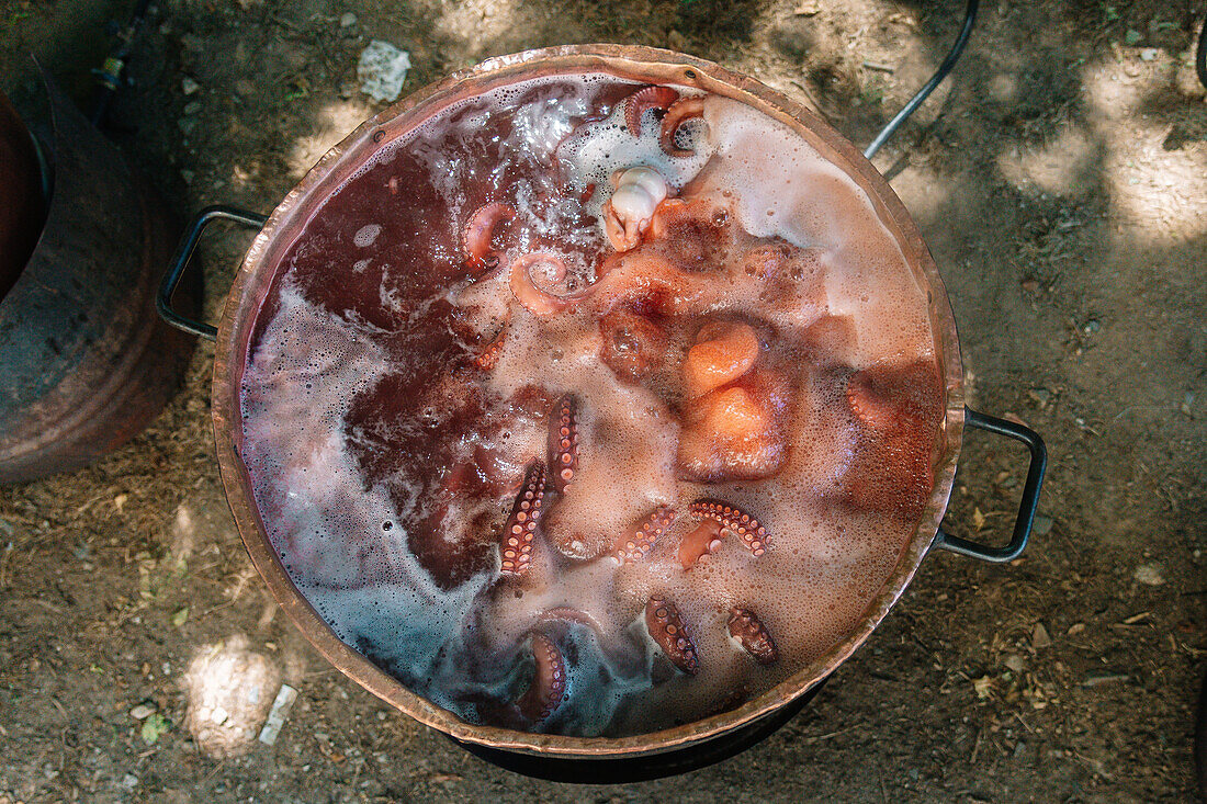 Top view of A traditional Galician octopus pot bubbles away as tentacles rise and fall in the simmering water