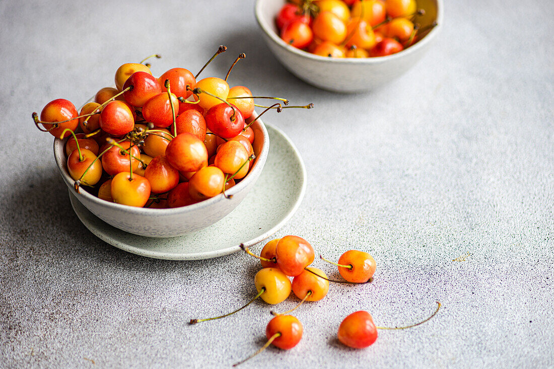 Bowl with organic ripe white sweet cherries on the concrete kitchen table
