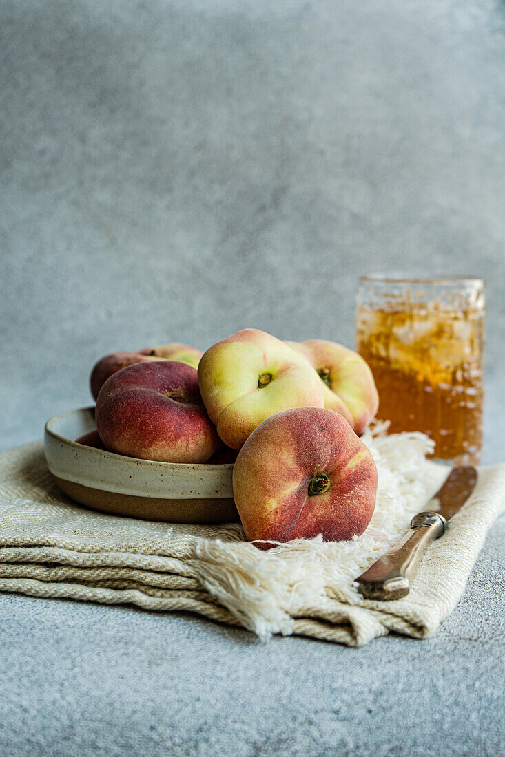 Teller mit Pfirsichsorte und Sommerlimonade mit Eis in der Nähe des Messers auf einer Serviette vor einem unscharfen Hintergrund