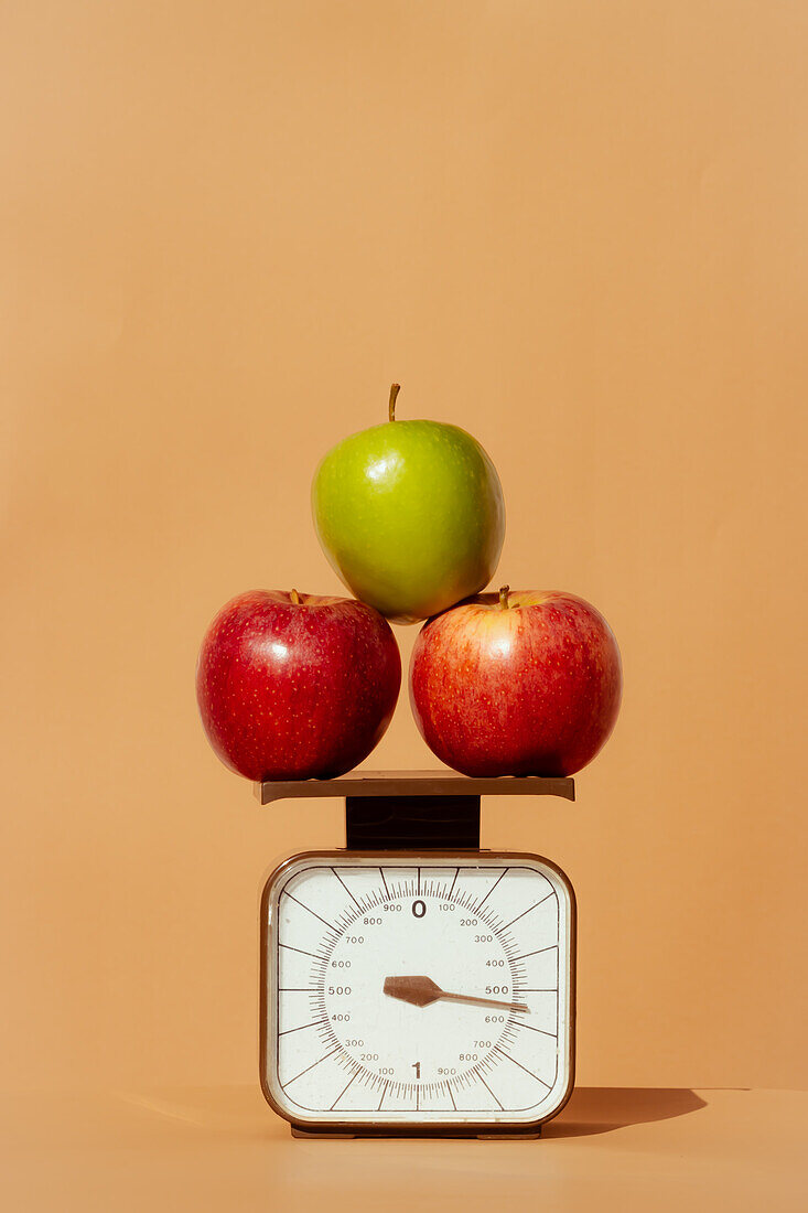 Frische und saftige rote und grüne Äpfel auf einer Waage als Teil einer gesunden kalorienkontrollierten Ernährung auf farbigem Hintergrund