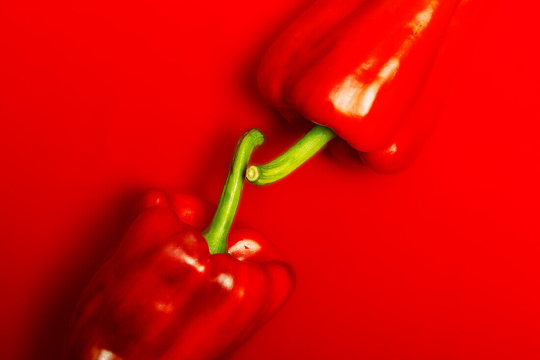 Top view of crop ripe red peppers placed together on red background