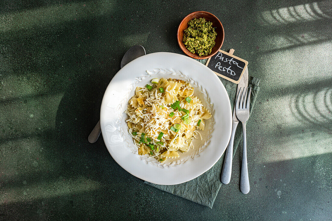 Overhead shot of a mouth-watering Farfalle pasta dish topped with pesto and parmesan, served on a stylish table setting.