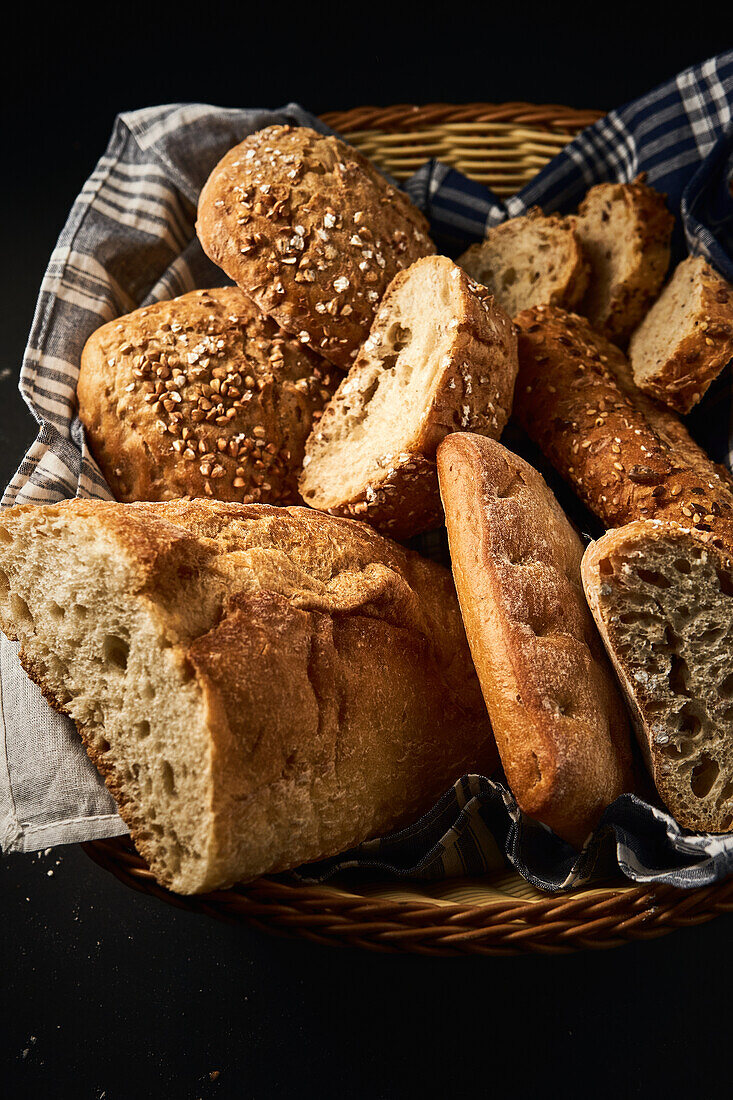Draufsicht auf leckeres, frisch gebackenes Brot mit knuspriger Kruste und Körnermischung, das auf einem Korb auf einer Serviette serviert wird