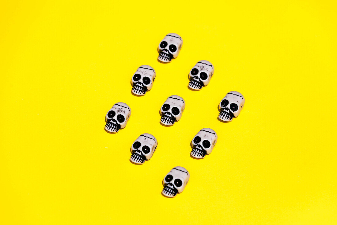 Vector illustration of small human skulls with creepy paint placed in symmetrical rhomb on vibrant yellow background