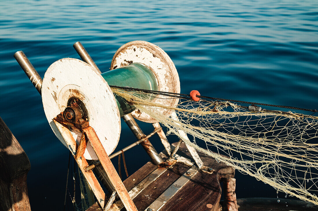 Rostige Metallspule mit Netz für den traditionellen Fischfang in der Nähe von blau kräuselndem Meerwasser in Soller, Mallorca, Spanien