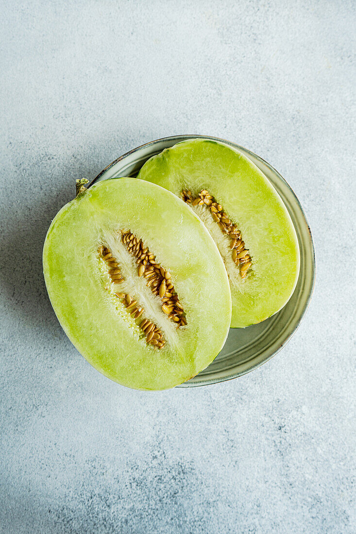 Top view melon split in half placed in a bowl on concrete background