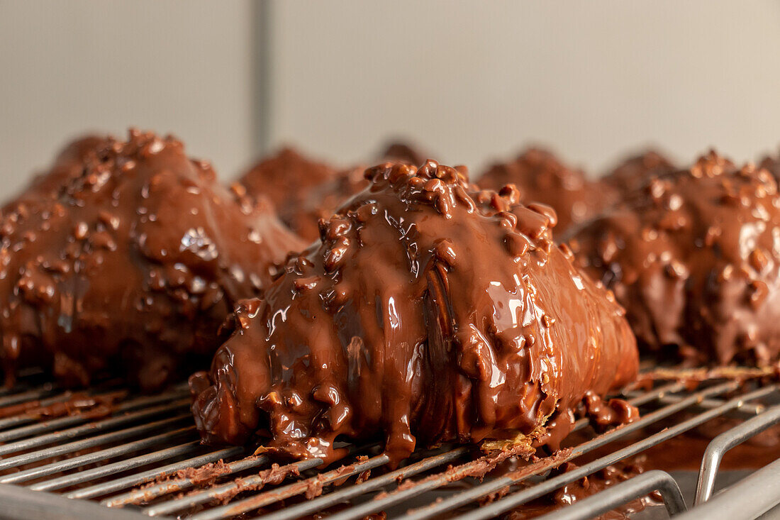 Closeup of delicious bread snacks covered in dripping chocolate and hazelnut served on metal grill grate against blurred background