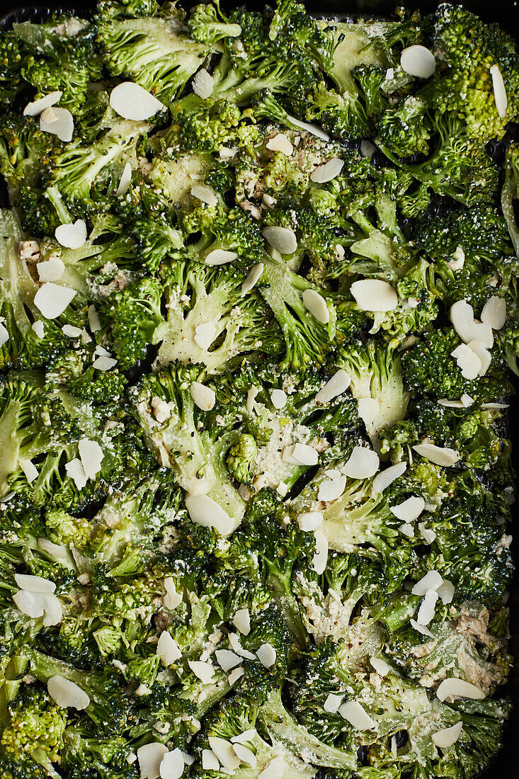 Von oben grüne Brokkolistiele mit Käse und Paprika auf hölzernem Hintergrund, die zum Kochen vorbereitet werden