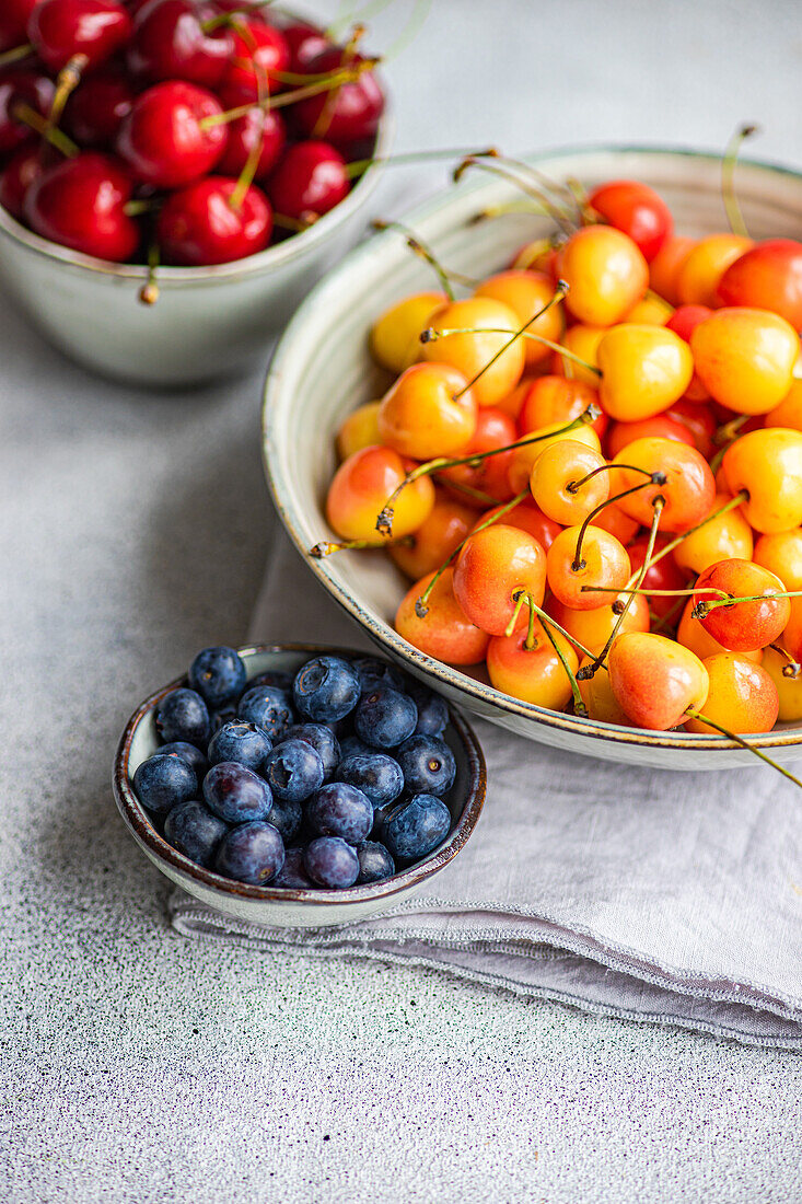 Bowl with organic ripe red and white sweet cherries and bowl with blueberry on the kitchen table