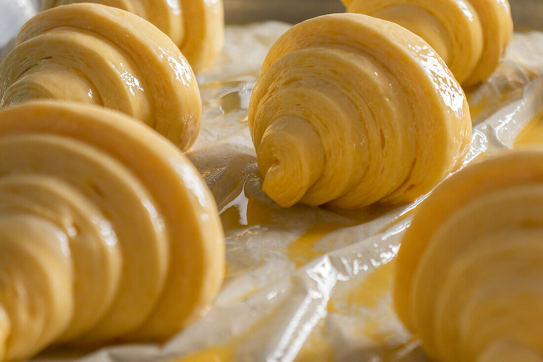 Köstliche rohe Croissants mit cremiger Butter auf einem Tisch mit weißer Polyäthylenabdeckung in einer Bäckerei