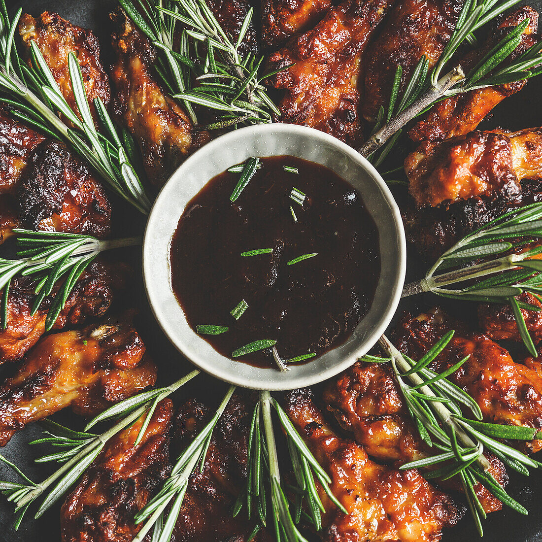 Close up of BBQ chicken wings with rosemary and homemade sauce. Cooking at home with marinated meat. Delicious finger food. Top view.