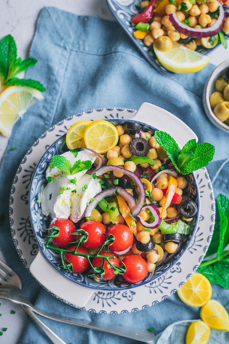 From above of delicious healthy salad with vegetables and herbs on plate over napkin