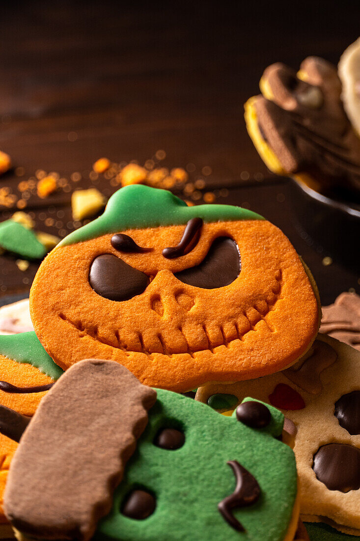 Focus of tasty Halloween cookies on plate placed on wooden table near rope