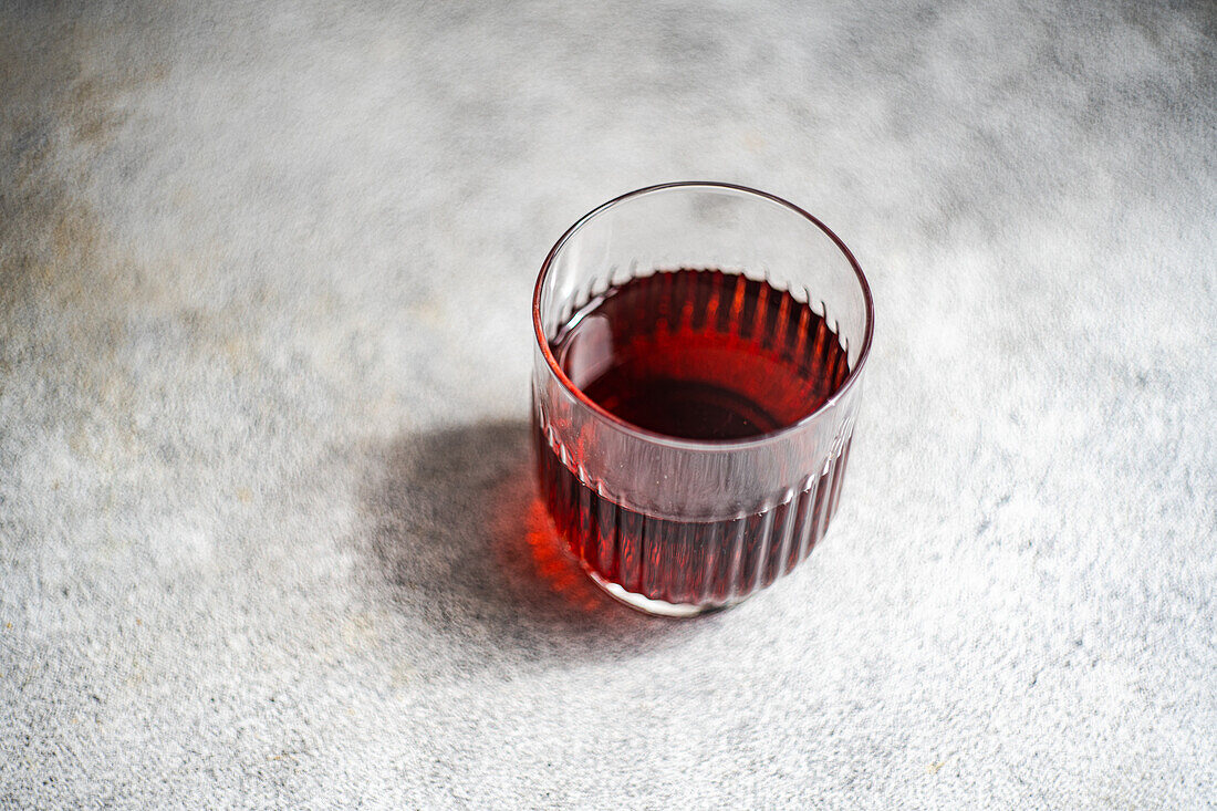 Hoher Winkel des traditionellen georgischen Rotweins Saperavi in einem transparenten Glas auf einem sauberen Tisch mit grauem Hintergrund