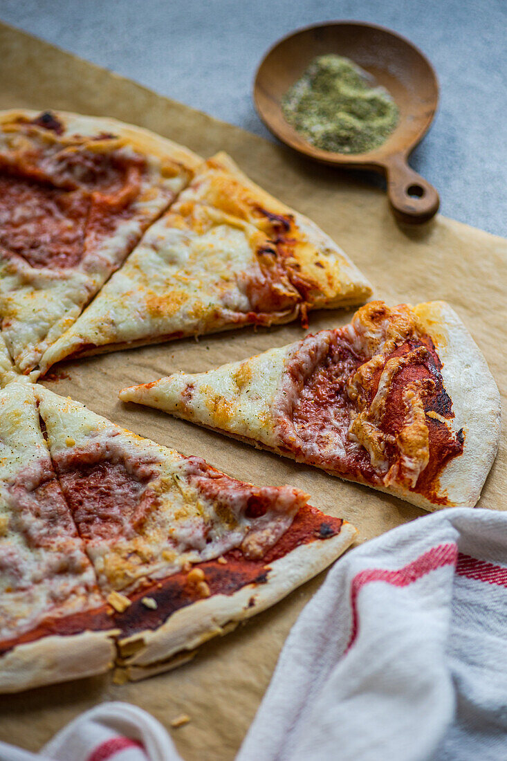 Fresh baked homemade pizza with italian herbs and parmesan cheese on the table