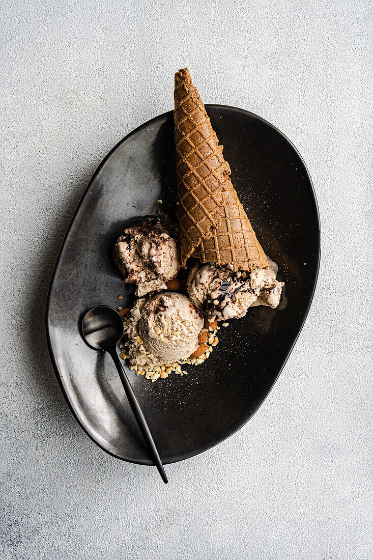 From above waffle cones with coffee and chocolate ice cream on the plate on concrete background
