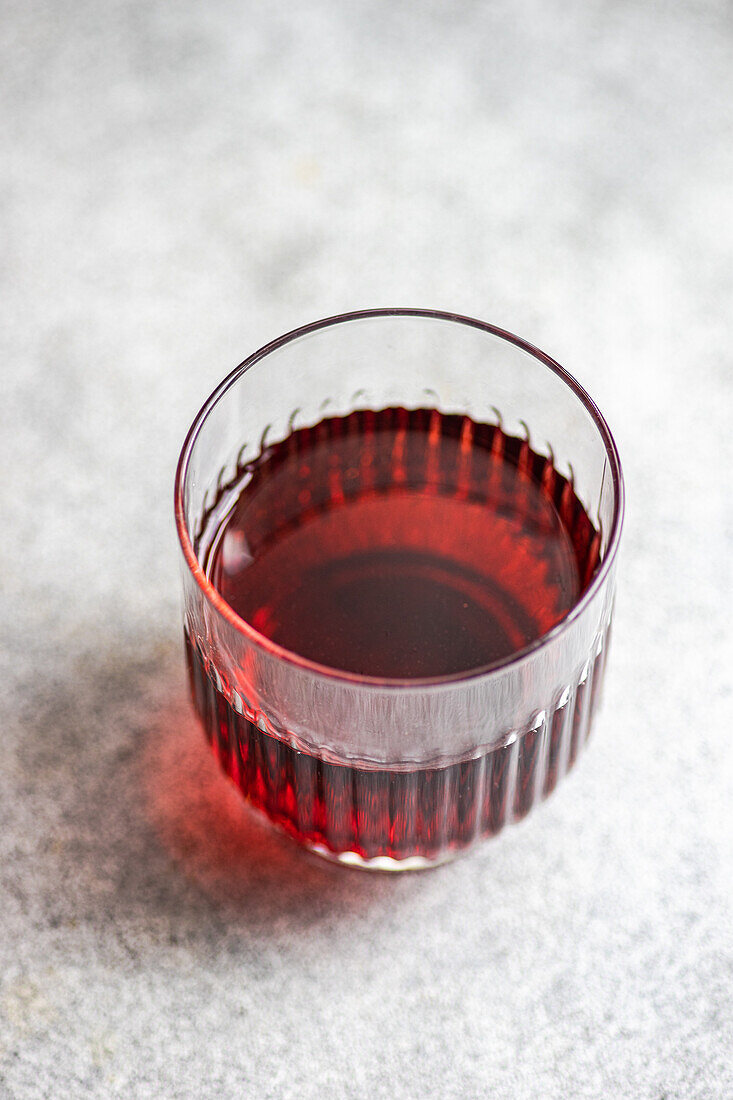 Hoher Winkel des traditionellen georgischen Rotweins Saperavi in einem transparenten Glas auf einem sauberen Tisch mit grauem Hintergrund