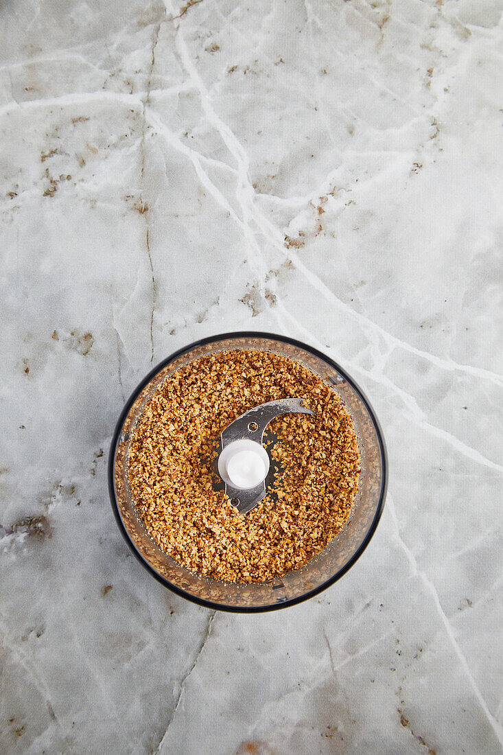 Top view of blender with crushed biscuits placed on marble counter during pastry cooking