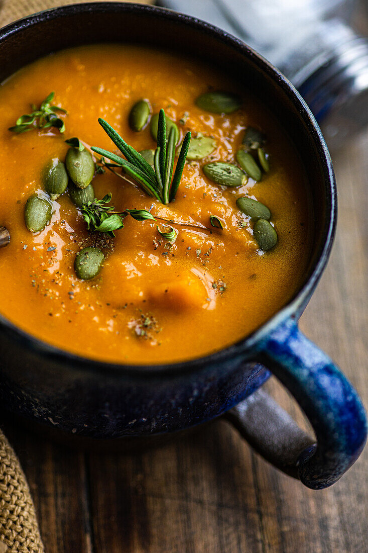 Leckere Kürbiscremesuppe mit Bio-Kräutern und Samen in blauer Vintage-Keramikschale