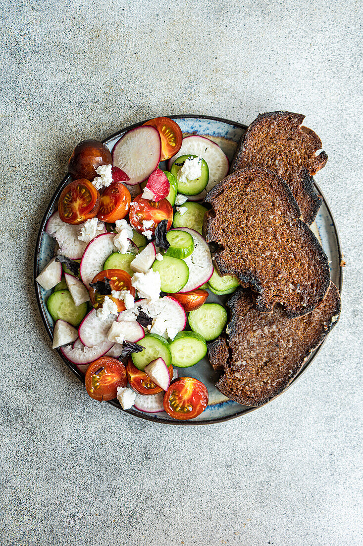 From above vegetable salad in Greek style with feta cheese on concrete background