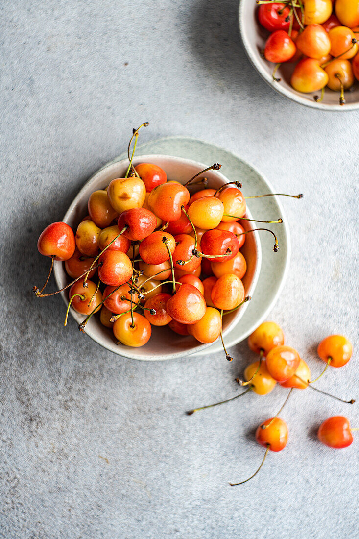 Bowl with organic ripe white sweet cherries on the concrete kitchen table