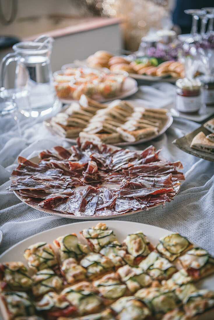 Appetizing fresh cooked snacks served on white plates on banquet table with tablecloth in restaurant