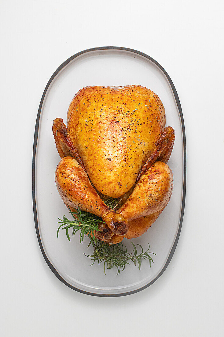 From above of whole Roasted Chicken ready to be served on a concrete plate plate on a white table