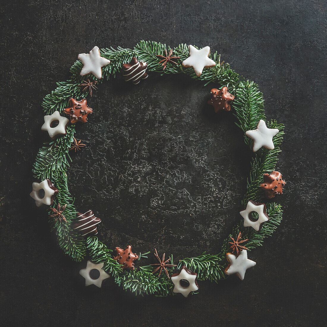 Christmas circle frame made with fir wreath and cookies on dark concrete kitchen table. Christmas background with copy space. Top view.